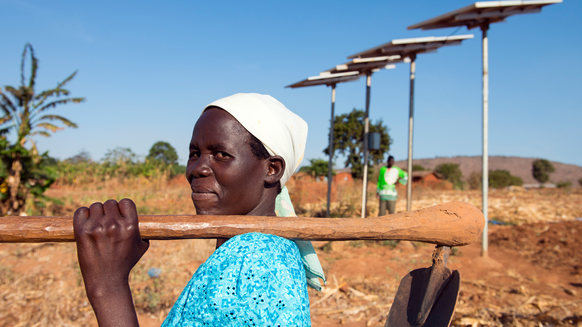 A woman farmer in Malawi in front of a solar system that provides electricity for the pump of a drip irrigation system