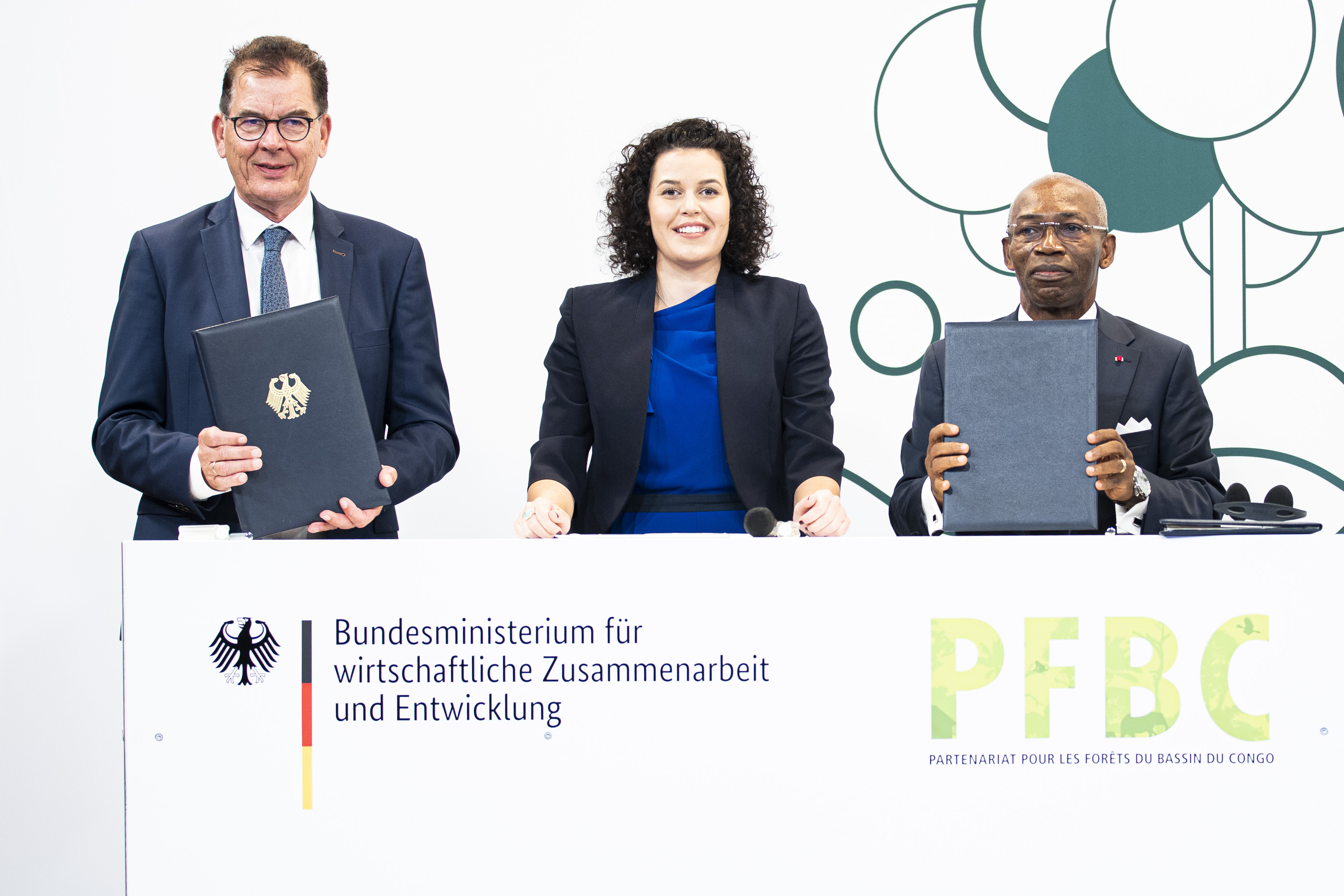 Bundesentwicklungsminister Gerd Müller (links) und Jules Doret Ndongo, Forstminister von Kamerun und Präsident der zentralafrikanischen Forstkommission (COMIFAC) (rechts), nach der Unterzeichnung der Deklaration über den Schutz des Regenwaldes im Kongobecken am 7. September 2021 mit Moderatorin Katie Gallus 